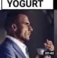 The Yogurt Founder, in a suit, eating yogurt and staring into the distance